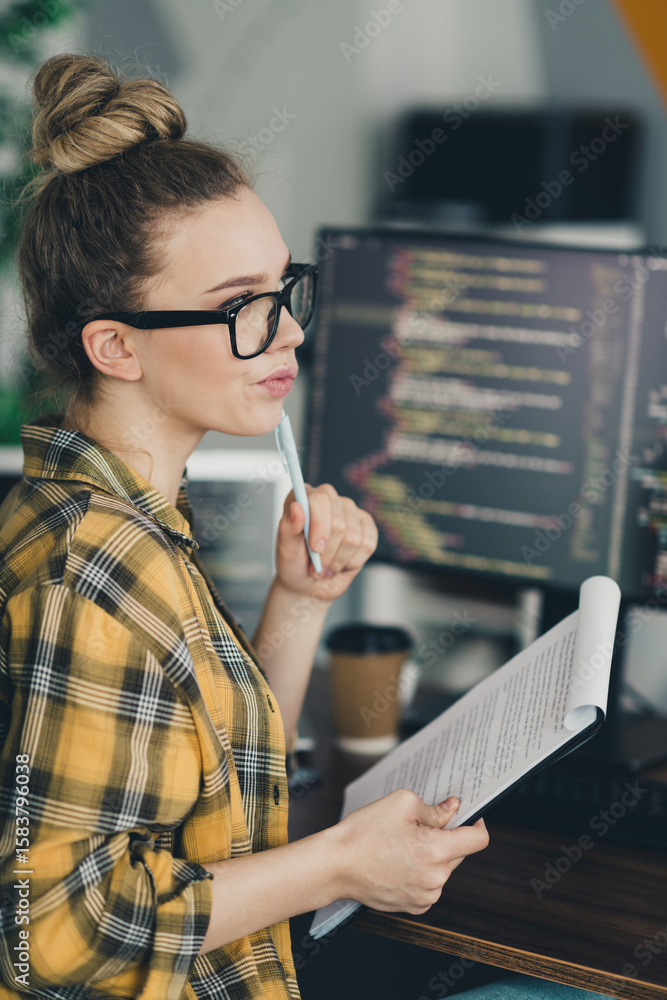 Poster young female professional analyzing code while working remotely in a modern workspace with a focused