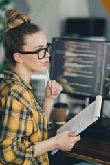 Young female professional analyzing code while working remotely in a modern workspace with a...