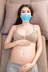 Pregnant woman is wearing protective medical mask to protect herself and future baby from...
