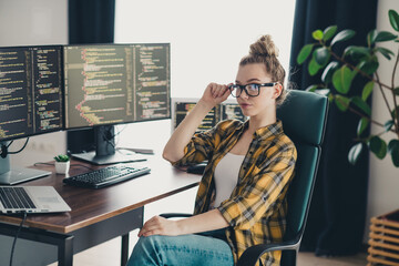 Young female programmer working on multiple monitors in a stylish home office