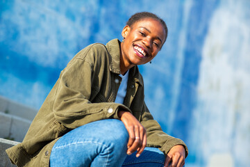 Smiling African woman in casual outfit sitting on outdoor steps