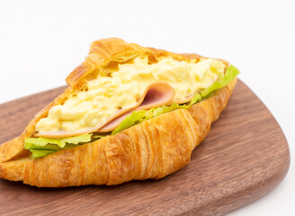Smoked Ham Egg Salad Croissant on Wooden Board isolated on white background side view of Savory Breakfast or Lunch