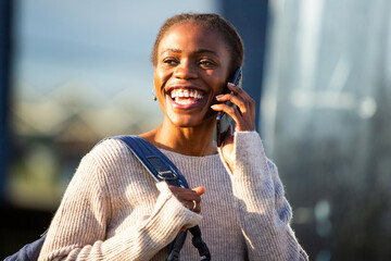 Smiling African woman having phone call in cozy sweater outdoors