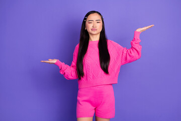 Cheerful young woman in a bright pink outfit posing confidently against a vibrant purple background