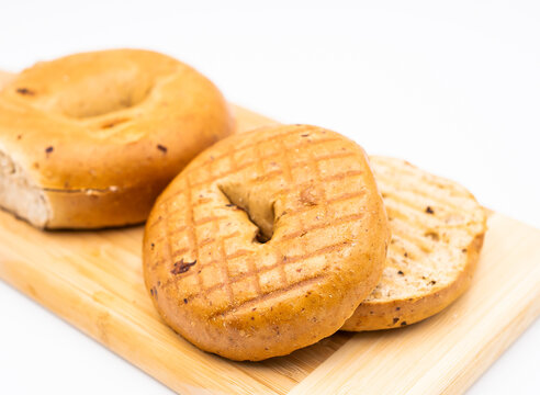 Toasted Whole Wheat Raisin Bagel on Wooden Board isolated on white background side view of Healthy Breakfast