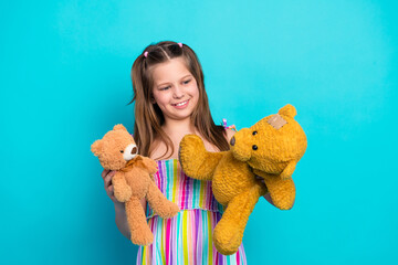 Smiling young girl holding teddy bears against a teal background showcasing a warm and playful...