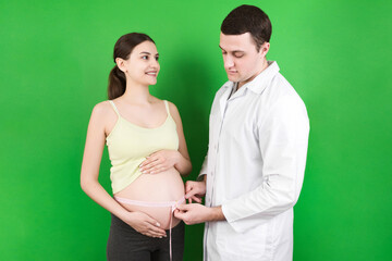 happy beautiful pregnant young woman touching her bare tummy while a doctor is measuring it
