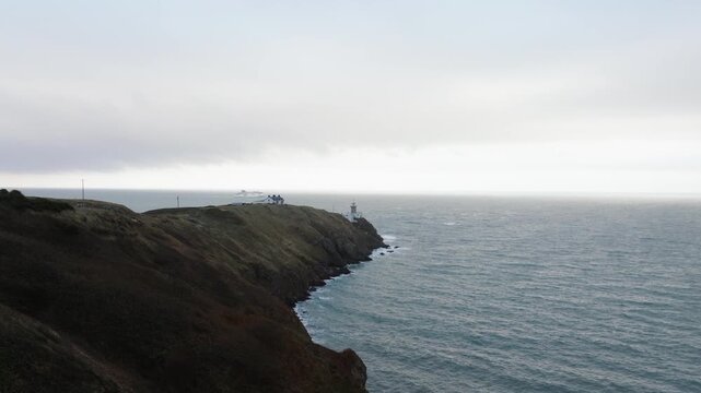Aerial footage of Baily Lighthouse in Howth, Dublin, Ireland on a windy and cloudy day in October. Ship passing by the lighthouse.