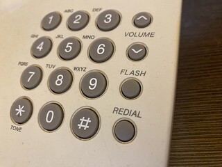 Close-up of a classic landline phone keypad, featuring prominent grey numerical buttons and...