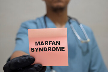 Doctor holds in hands a card with the name of the Marfan syndrome. Medical concept