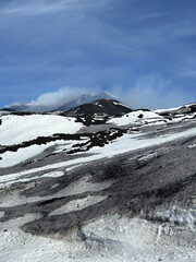 Snow-covered volcanic landscape with dark rocky terrain under a clear blue sky, showcasing the...