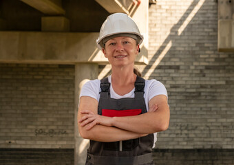 Construction worker in safety gear smiles confidently under a concrete structure with sunlight...