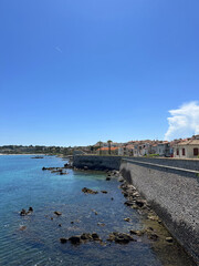Coastal view featuring a serene waterfront with clear blue water, rocky shoreline, and charming...