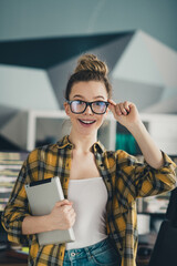 Bright young female freelancer holding a tablet, showcasing enthusiasm in a casual modern workspace