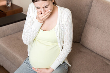 Pregnancy Morning Sickness. Pregnant Woman Having Nausea Feeling Bad in Sofa at the Home
