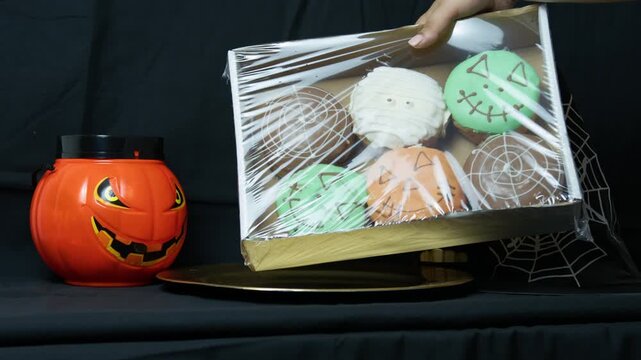 placing Halloween dounuts near pumpkin and witch hat