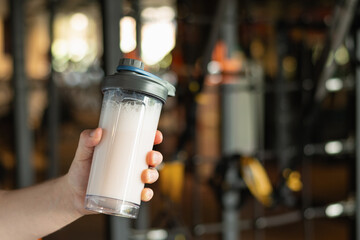 Close up of hand with protein shaker at gym. Fitness healthy lifestyle concept. Supplement product,...