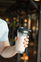 Protein shaker in hand at gym. Fitness healthy lifestyle concept. Supplement product, creatine,...