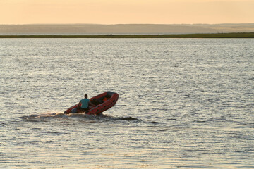  A man controls the motor on an inflatable boat. The boat's bow is raised.