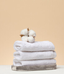 A stack of white folded towels lies on a marble stand, with natural cotton inflorescences on top