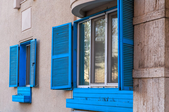 Blue shutters on residential building with open windows - Powered by Adobe