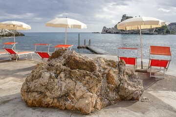 taormina, italien - liegestühle mit badesteg und blick zur isola bella
