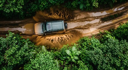 Aerial view of a green SUV driving through muddy terrain amidst lush green foliage creating a dynamic scene.