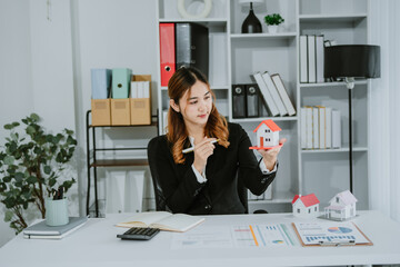 Asian real estate agent in modern office consulting clients, showcasing properties with a laptop,...