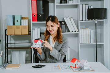 Close-up image of a male real estate agent holding a house model at his desk. property investment