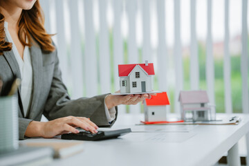 Close-up image of a male real estate agent holding a house model at his desk. property investment