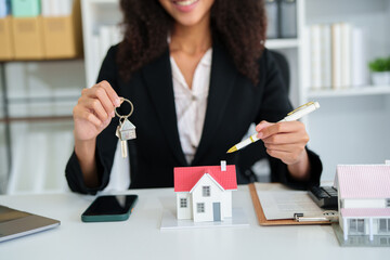 Confident American woman real estate agent stands proudly outside a modern home, radiating...