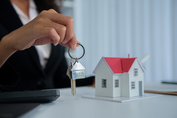 An African American female real estate agent presents a house model to a client, discussing...