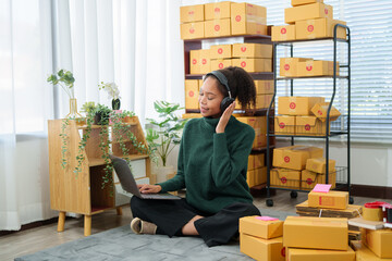 Young asian entrepreneur managing retail orders and preparing packages for dispatch from her...
