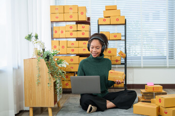 Young asian entrepreneur managing retail orders and preparing packages for dispatch from her...