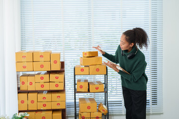 Young asian entrepreneur managing retail orders and preparing packages for dispatch from her...
