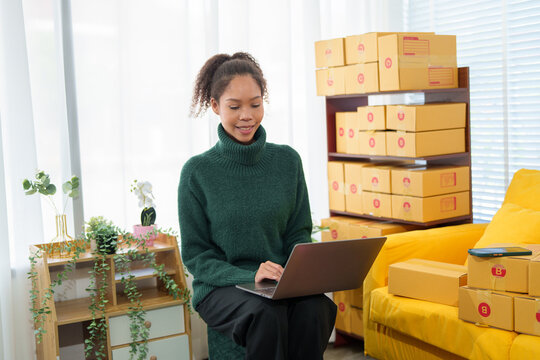 Startup SME small business entrepreneur of freelance Asian woman wearing apron using laptop and box to receive and review orders online to prepare to pack sell to customers, online sme business ideas.