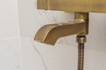 Golden faucet with plaque in shower closeup. Rusty deposits of hard water. Calcareous plaque