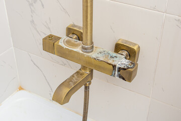 Plaque from hard water on gold shower faucet. Streaks or rust. Blue calcareous plaque