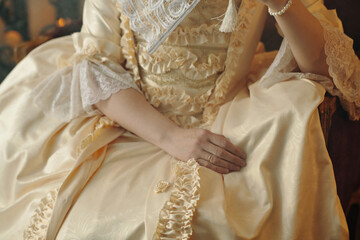 Caucasian middle aged woman sitting in ornate Baroque style dress holding lace fan, showing...