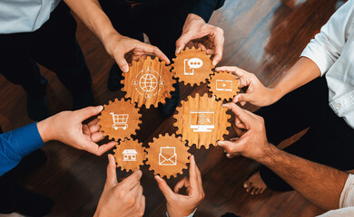 Hands from diverse individuals hold gears with icons representing digital marketing and e-commerce. This image illustrates the synergy of teamwork and innovation in business contexts. Amity