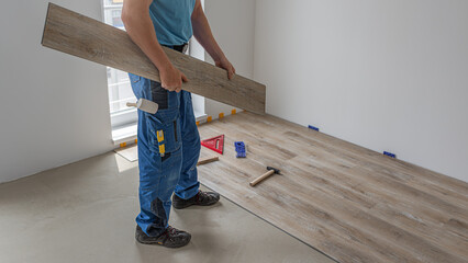 Floating floor work. The worker's hands holding a vinyl plank flooring with click system.