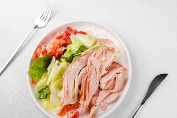 Protein salad with turkey, cheese and vegetables in white bowl with cutlery for fitness meal plan or diet food concept