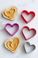 Heart shaped peanut butter sandwiches and cookie cutters lying on white marble