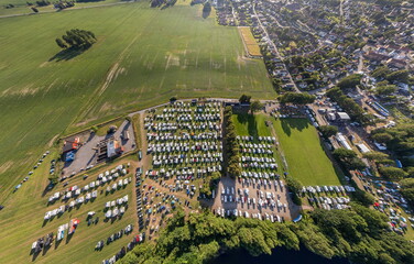 Large countryside campsite with many RVs near a field, panoramic aerial view from drone