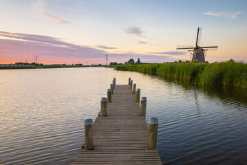 Beautiful evening view of a wooden jetty with windmill at the shore of lake Rottemeren, north of...