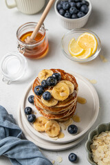 Stack of American banana pancakes with fresh blueberries, honey and almond petals. Healthy eating. Morning tasty homemade breakfast. Top view, selective focus.