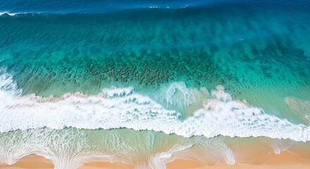 Obraz premium Stunning Aerial View of Turquoise Ocean Waves Crashing Onto a Pristine Sandy Beach on a Sunny Day