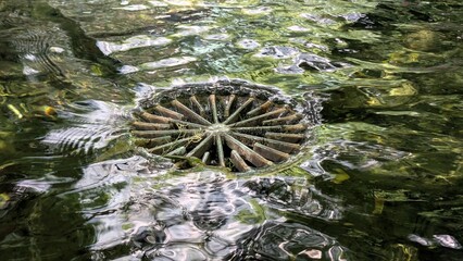 Old round drain in a fountain against the background of water