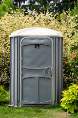 View of single portable toilet in park.