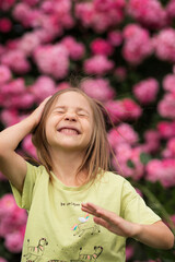 a blonde girl is laughing, and behind her are beautiful pink flowers